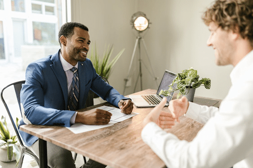 Séance de coaching professionnel entre deux hommes Séance de coaching professionnel ou d’entretien professionnel entre deux hommes assis à une table, en discussion dans un bureau lumineux.