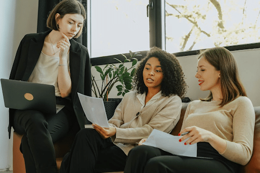 coaching professionnel, indispensable en entreprise Trois femmes assises ensemble dans un cadre professionnel, en échange autour d’un ordinateur portable et de documents.