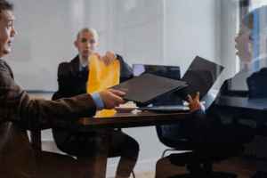 Réunion de travail en salle de réunion vitrée, avec échange de dossiers et discussion entre plusieurs professionnels