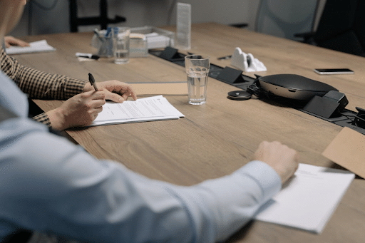 Personnes en réunion autour d’une table de conférence, en train de prendre des notes et d’échanger dans un cadre professionnel.