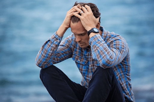 Coaching professionnel dans les période difficiles Coaching professionnel dans les moments difficiles. Homme assis en extérieur exprimant un moment de stress ou de réflexion profonde.